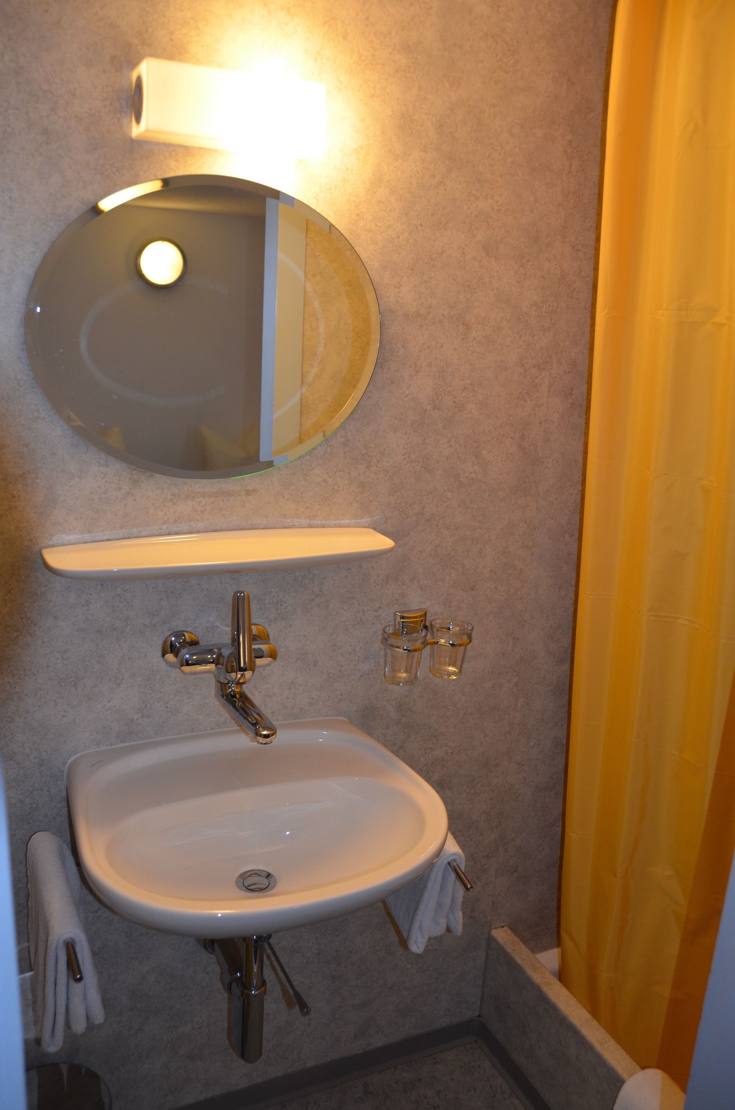 A bathroom with a sink, mirror, and shelf.
