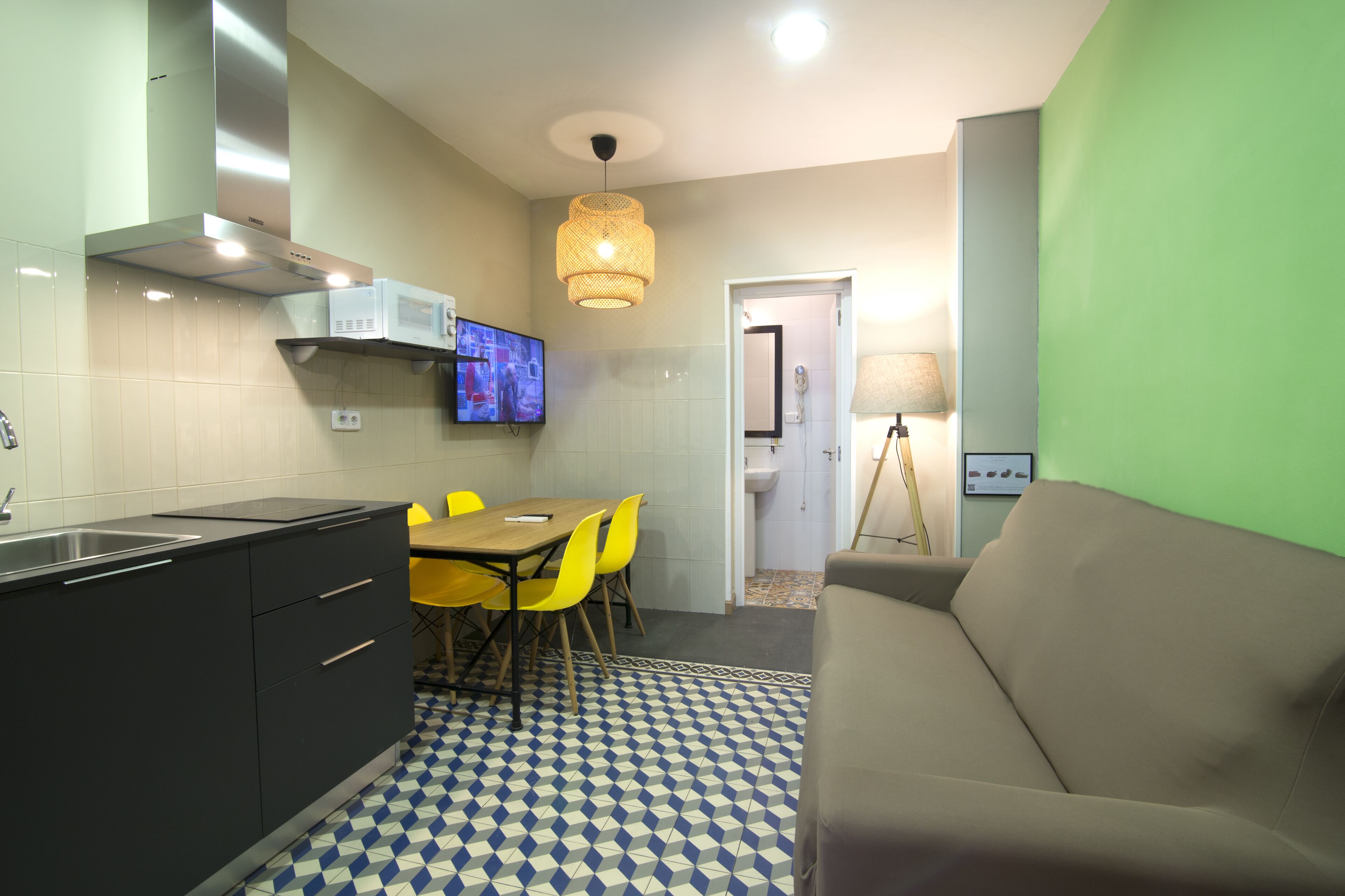 A compact kitchen with a dining area, a sofa, and a television.