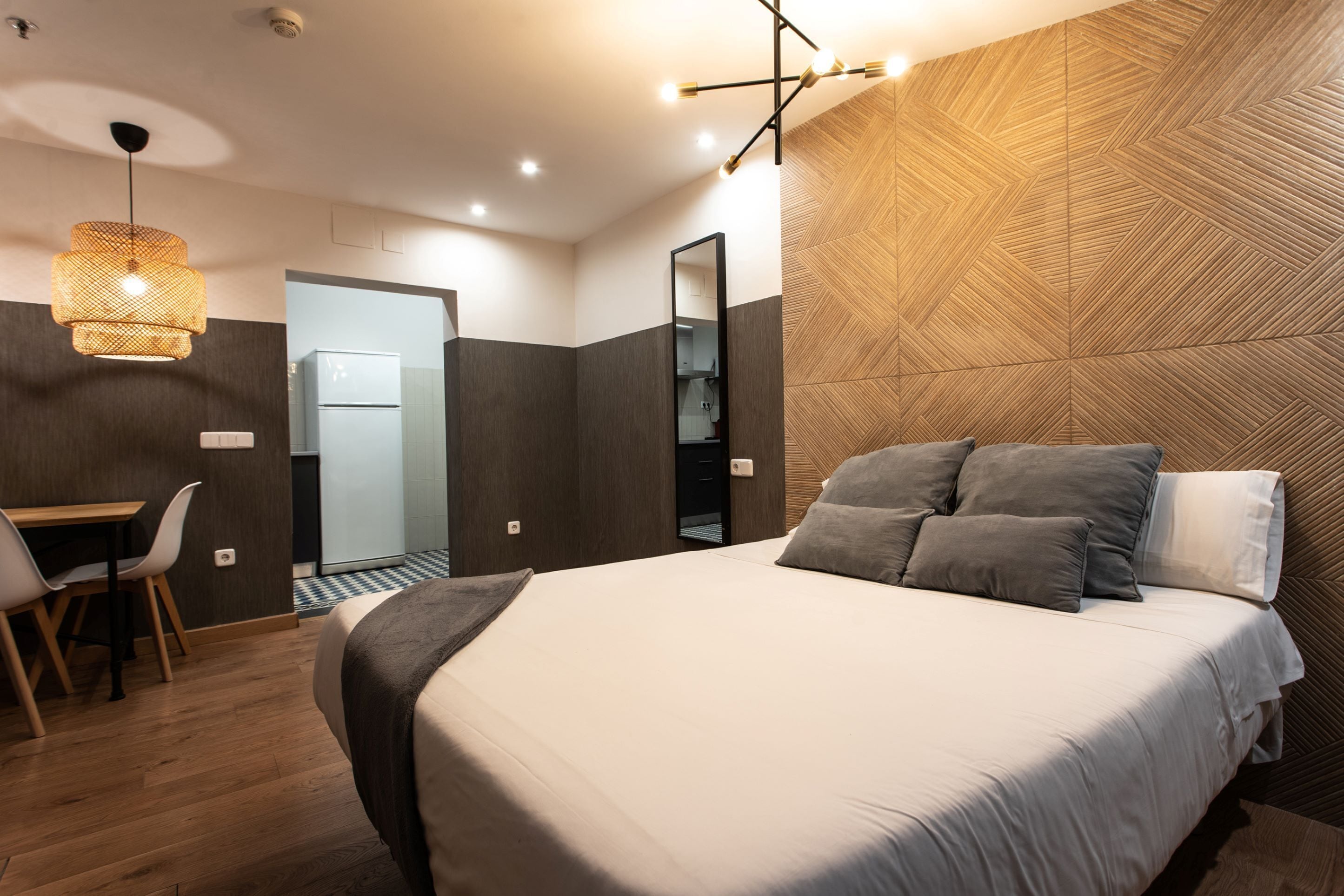 Une chambre à coucher moderne avec un grand lit, un bureau et un miroir.