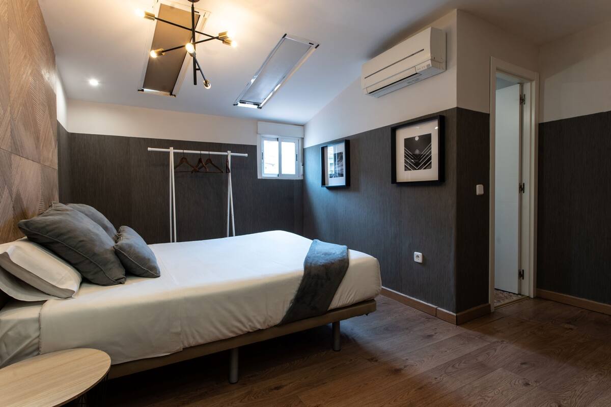A modern bedroom with a bed, bedside table, and a ceiling light fixture.