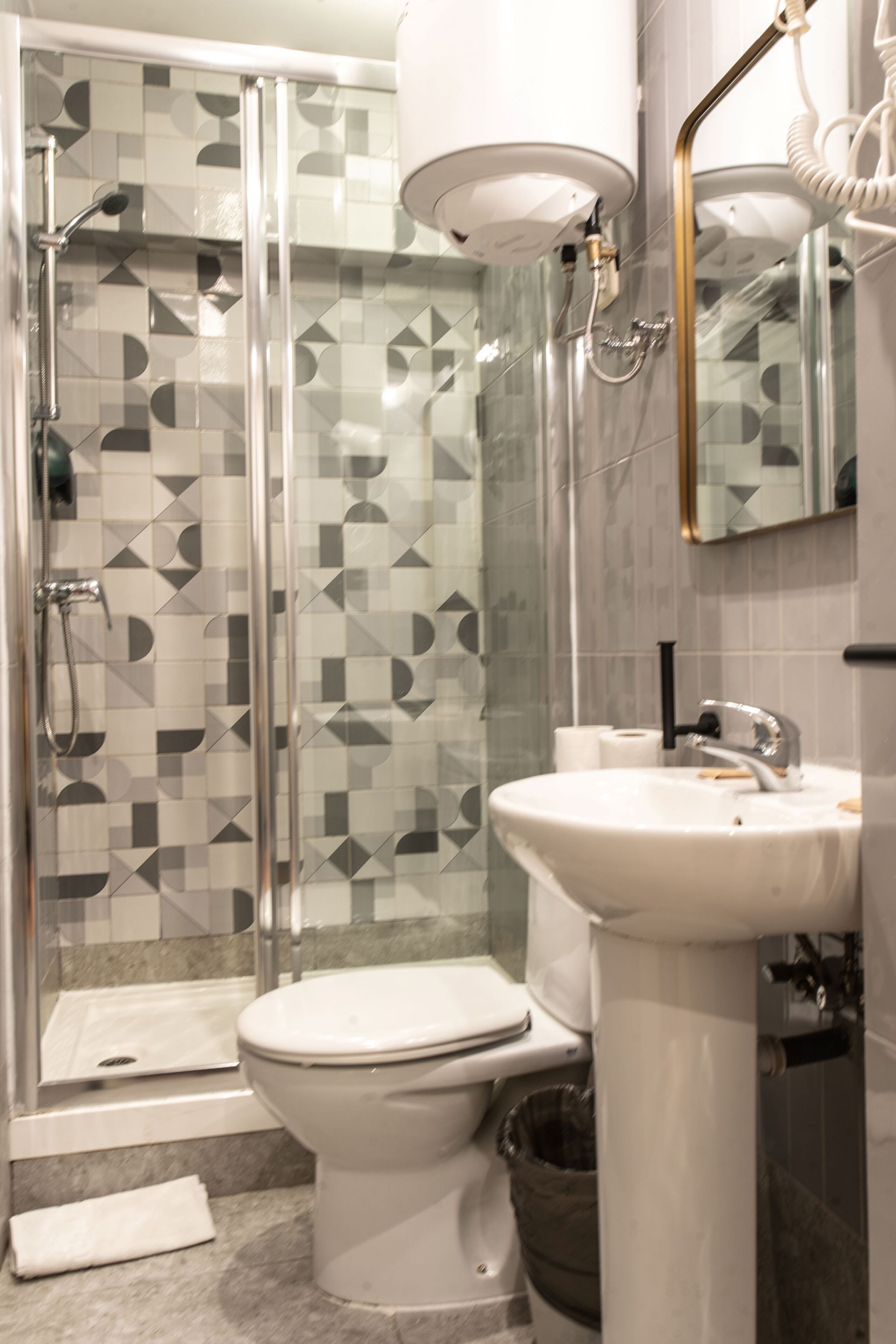 A modern bathroom with a glass-enclosed shower, a white toilet, and a pedestal sink.