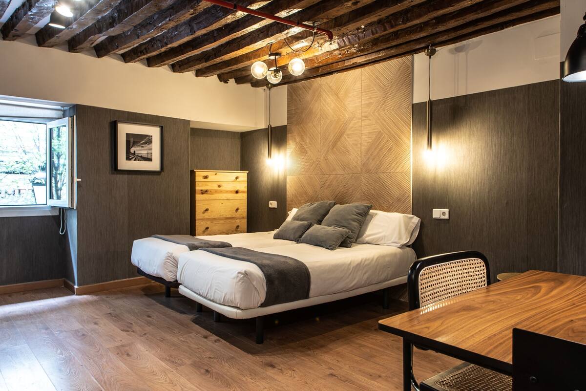 A bedroom with a bed, wooden dresser, and a desk with a chair.