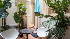 A small, enclosed patio area with two white chairs, a small table, and several potted plants. - Suites You Zinc (Madrid)