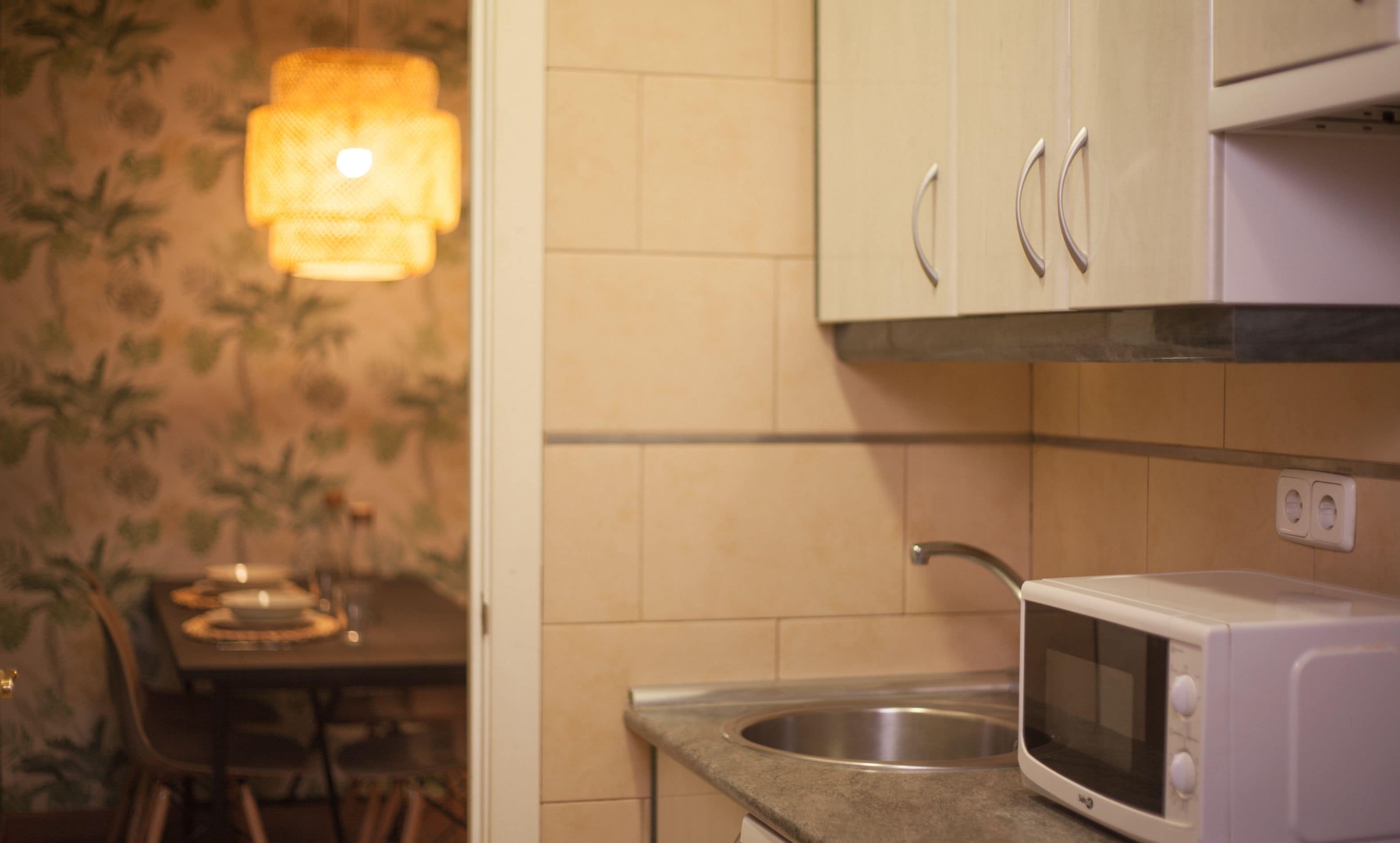 A kitchen with a microwave, a sink, and cabinets.