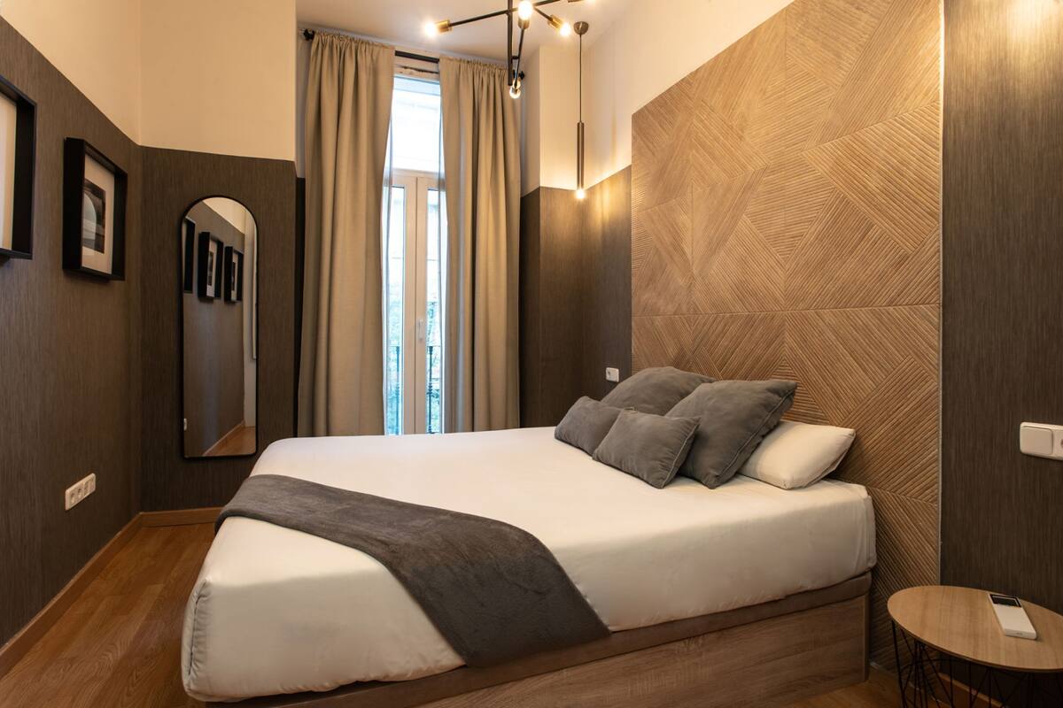 A modern hotel room with a large bed, a small round table, and a mirror on the wall.