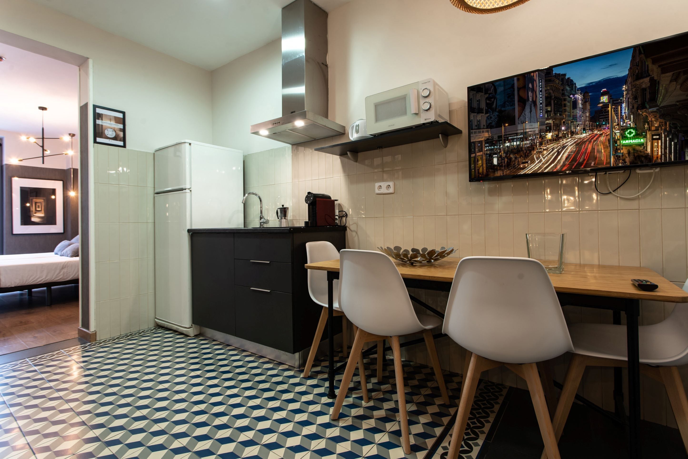 A compact kitchen with a microwave, stove, and a dining area with chairs and a table.