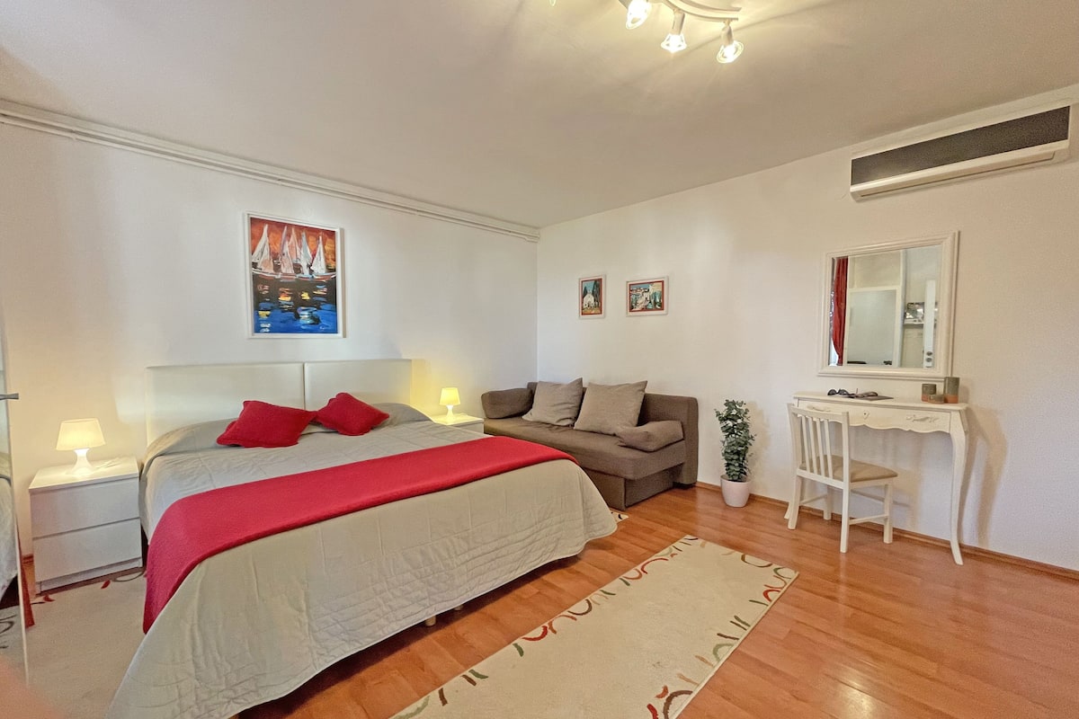 Un dormitorio con cama, mesita de noche, cómoda, espejo y ventana.