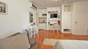 Un espace de vie compact comprenant un coin cuisine, un coin repas et un espace détente avec un canapé et un lit.