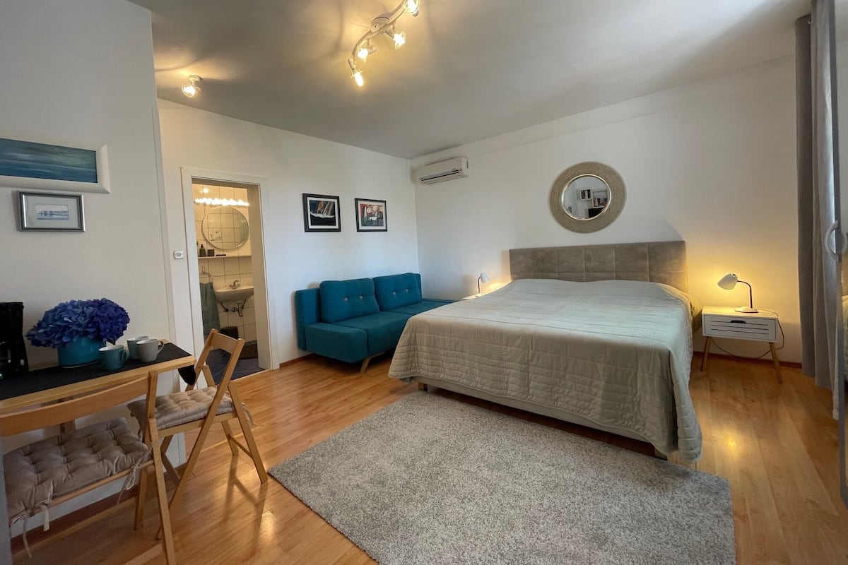 Un dormitorio moderno con cama, escritorio, silla, sofá y espejo.