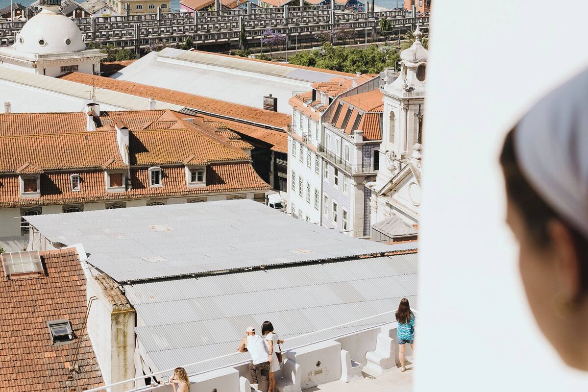 Vista de un paisaje urbano costero con un puente destacado al fondo, un edificio con forma de cúpula y una persona sentada en una azotea.