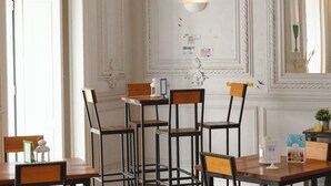 Un comedor con mesas y sillas de madera, una araña y una lámpara de pared.