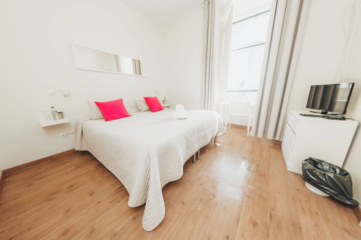 Una habitación de hotel con una cama, un televisor y una ventana.