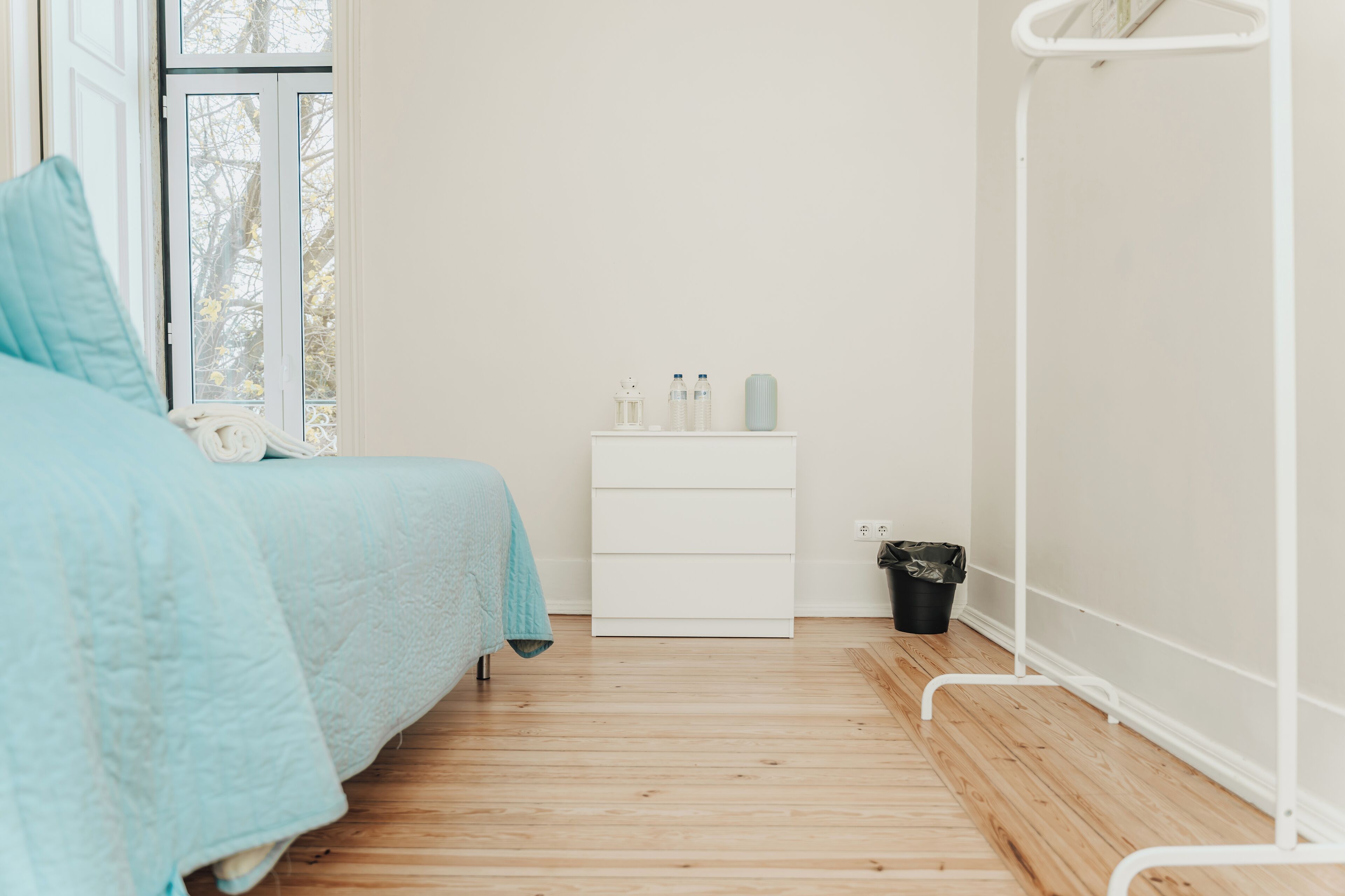 A minimalist bedroom with a bed, a nightstand, and a window.