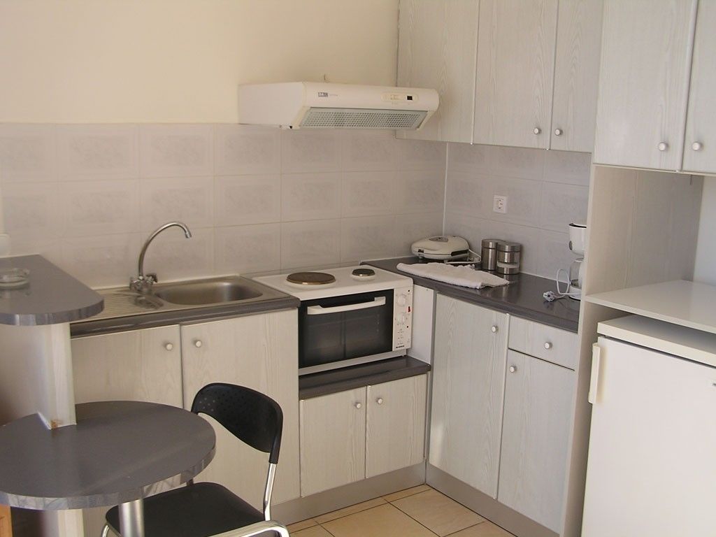A compact kitchen with a sink, stove, microwave, and a small refrigerator.