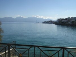 A waterfront view with a clear sky, calm water, and distant mountains.