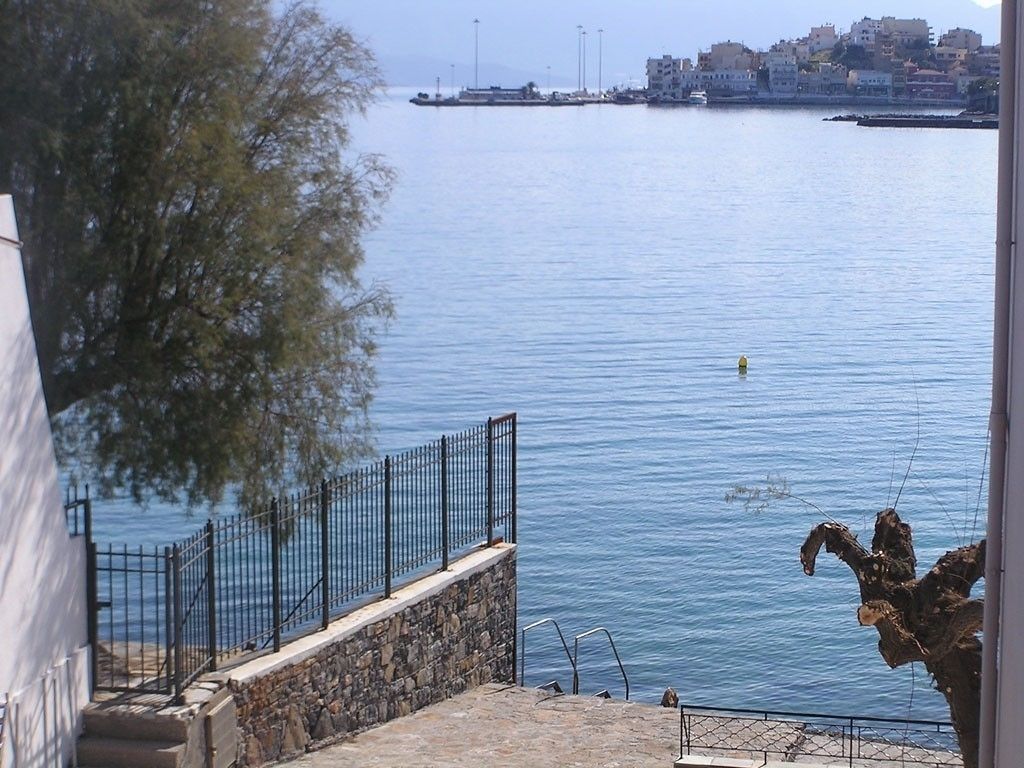 A coastal view with a stone staircase leading to a balcony overlooking calm waters.