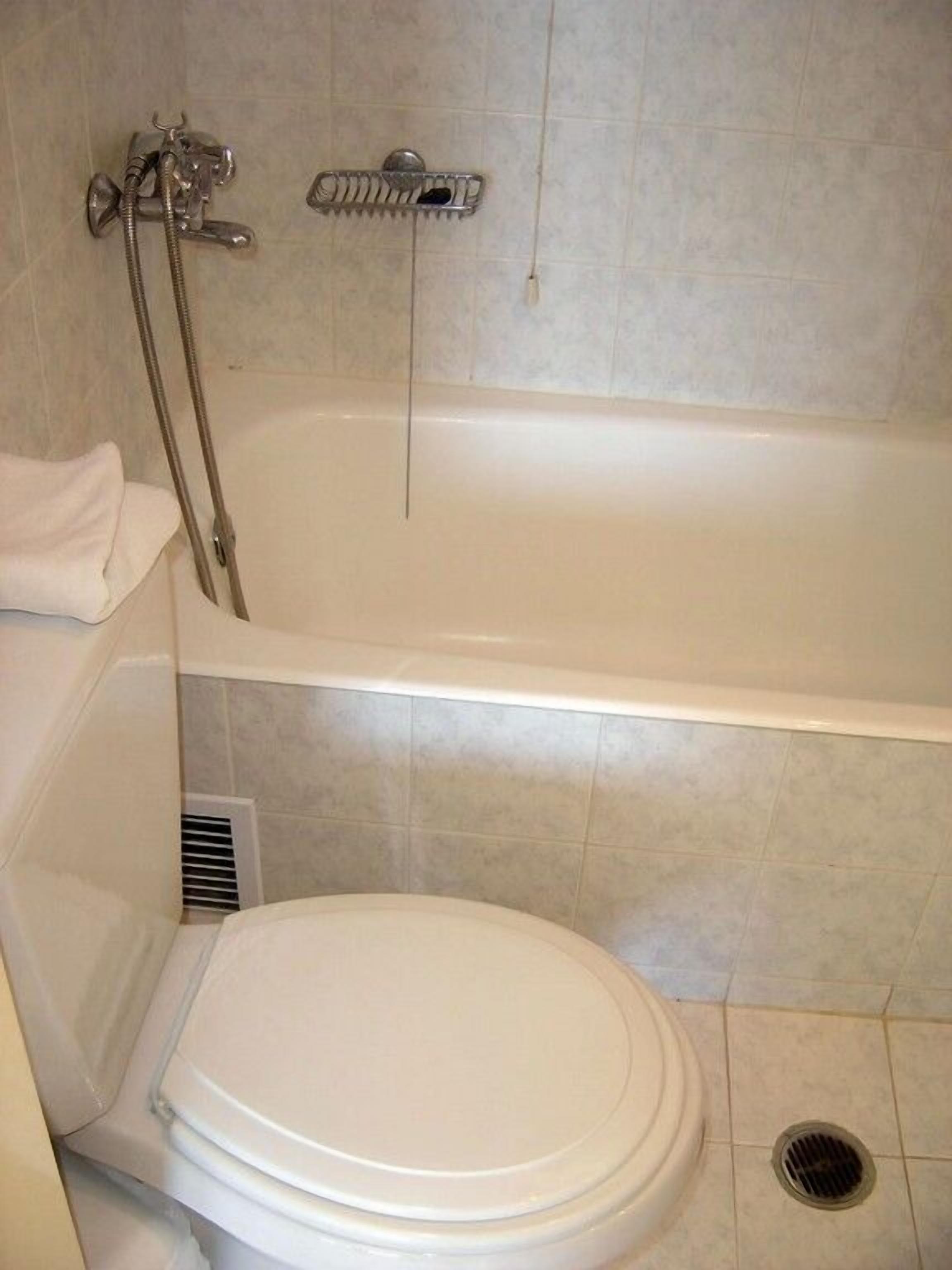 A bathroom with a white bathtub, a toilet, and a showerhead.