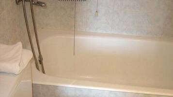 A bathroom with a white bathtub, a toilet, and a showerhead.