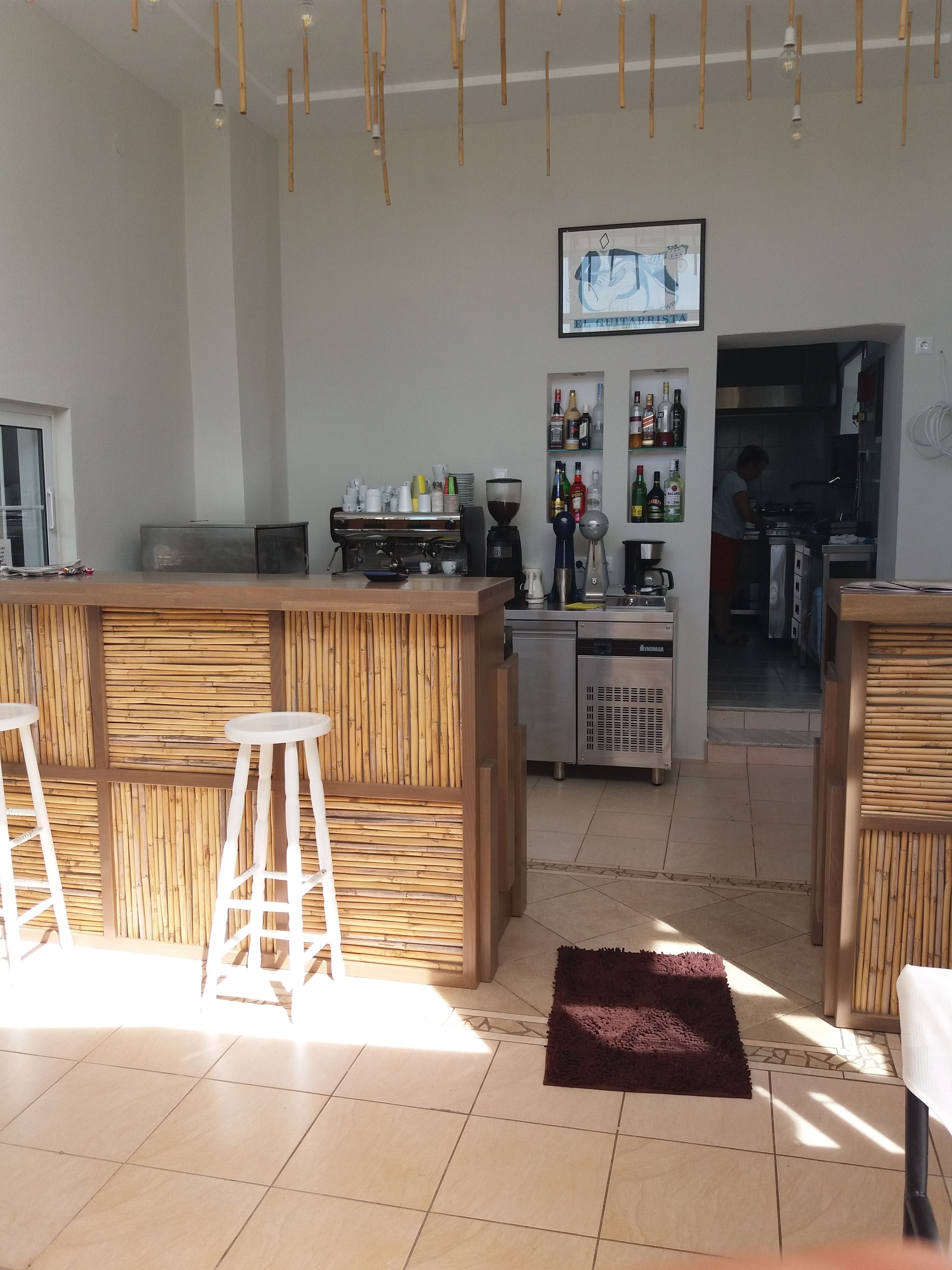 Cuina moderna amb barra, equipada amb cafetera i diverses ampolles.