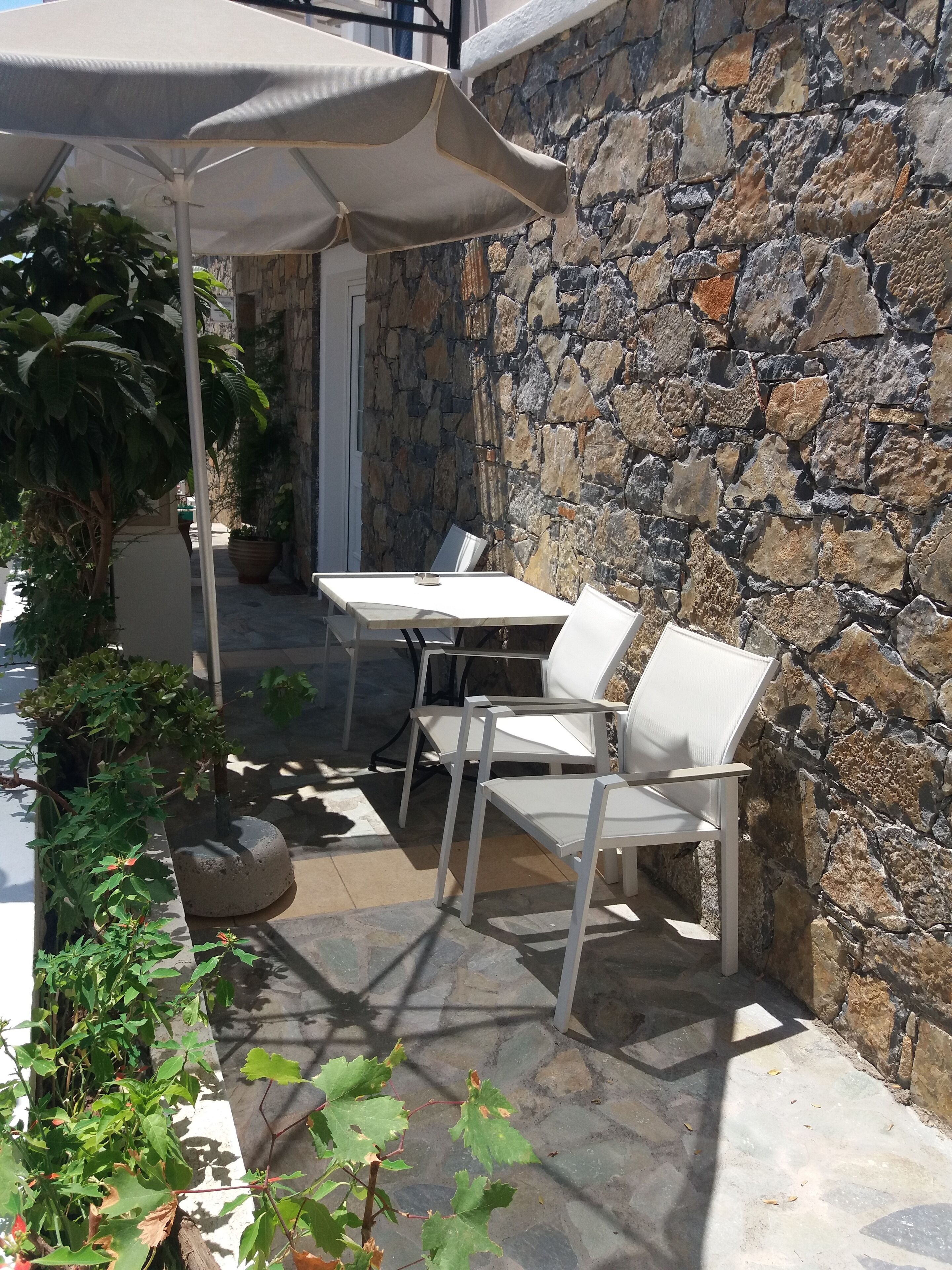 An outdoor seating area with a stone wall backdrop, a table, and chairs.