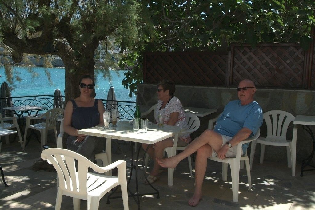 Drei Personen sitzen an einem Tisch mit Meerblick.