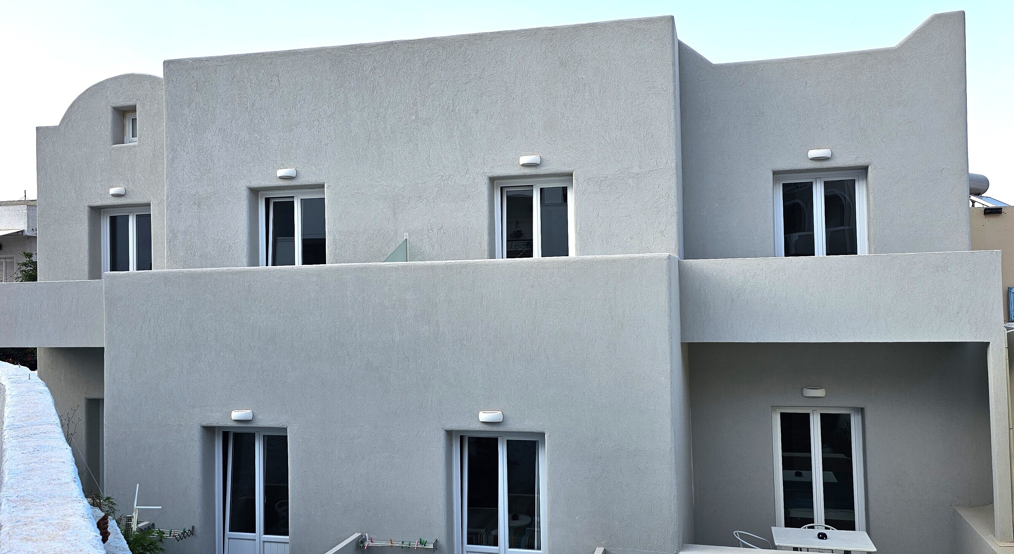A modern building with a flat facade, multiple windows, and a balcony.