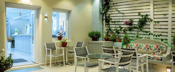 Zona de recepción con mostrador, sillas y plantas en macetas.