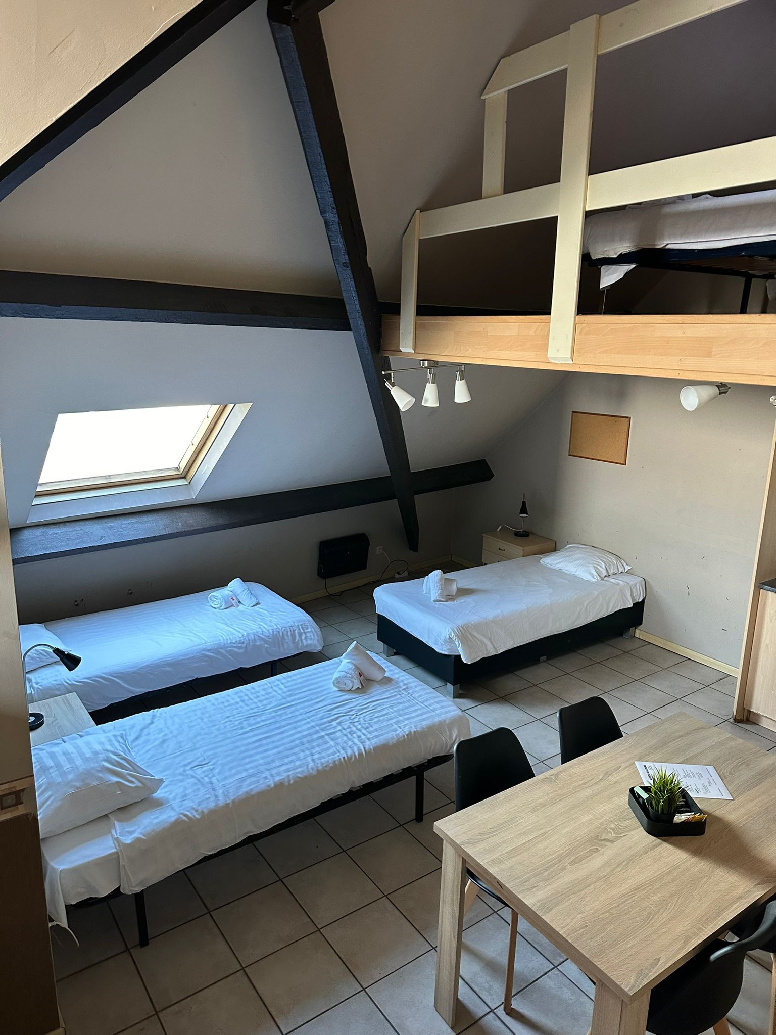 Un dormitorio con literas, un tragaluz, una mesa y una silla.
