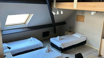 Un dormitorio con literas, un tragaluz, una mesa y una silla.