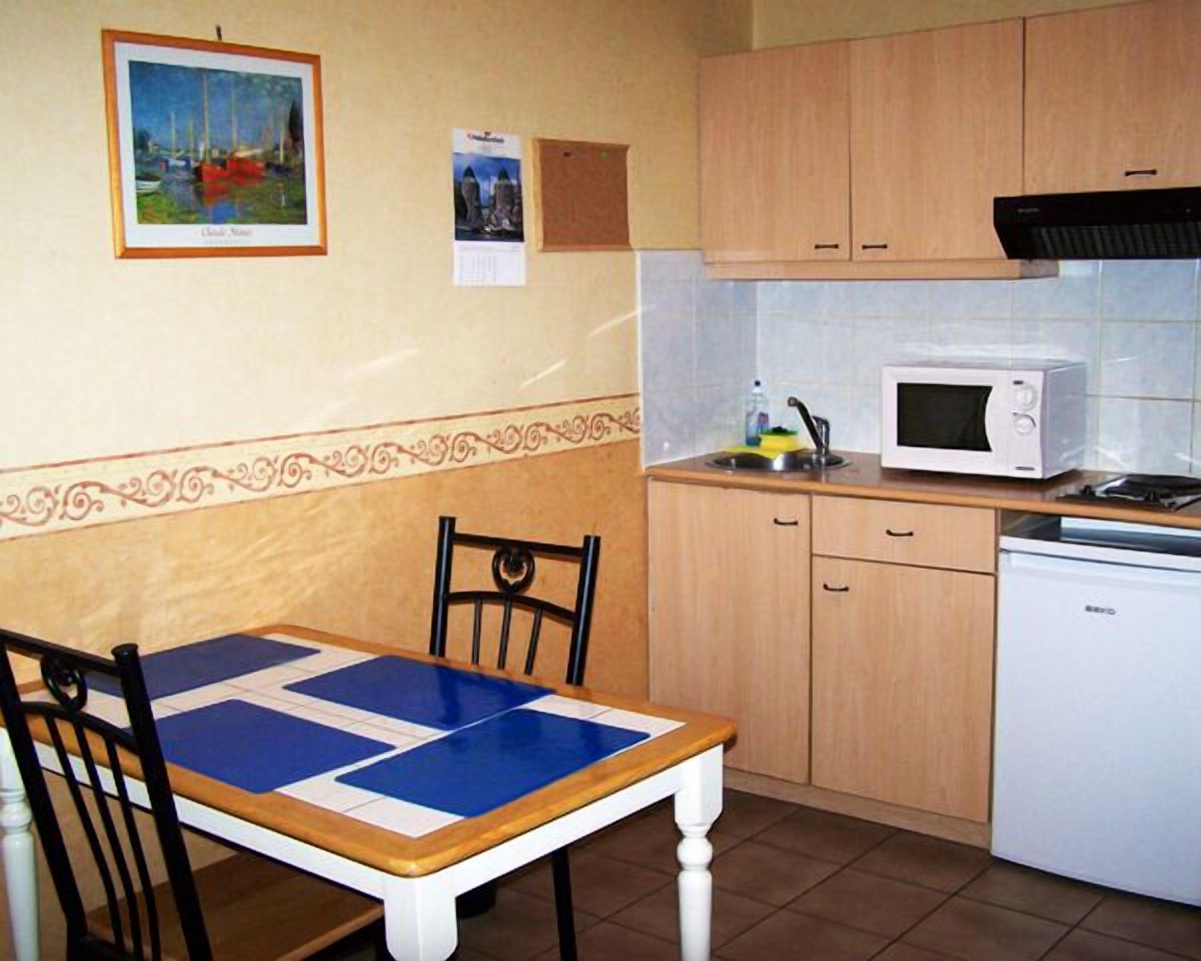 A compact kitchen with a dining table, chairs, a microwave, and a dishwasher.
