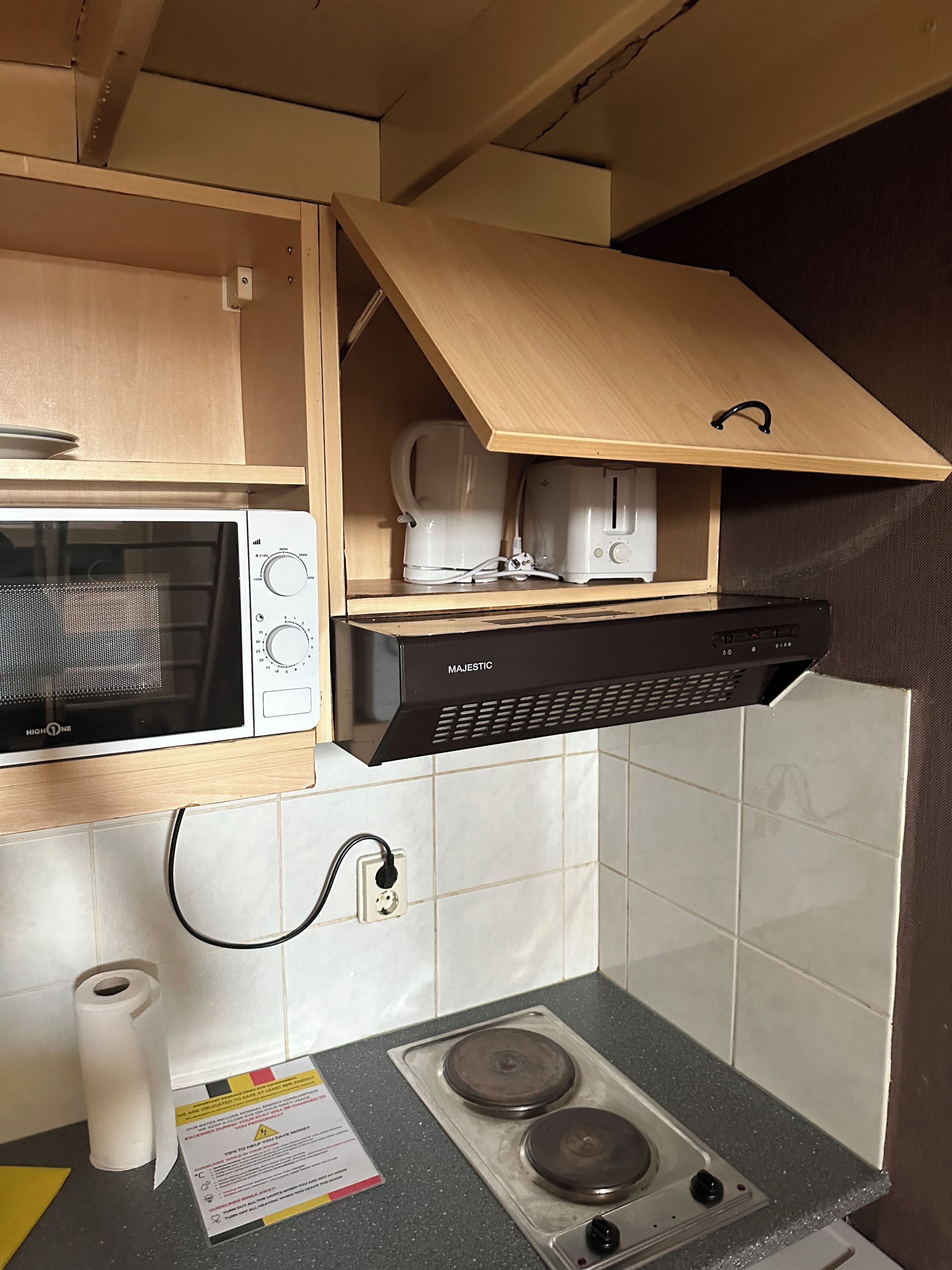 A compact kitchen with a microwave, coffee maker, toaster, and a stove.
