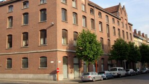 Un edificio grande de ladrillo con varias ventanas y una señal roja que indica 'no entrar'.