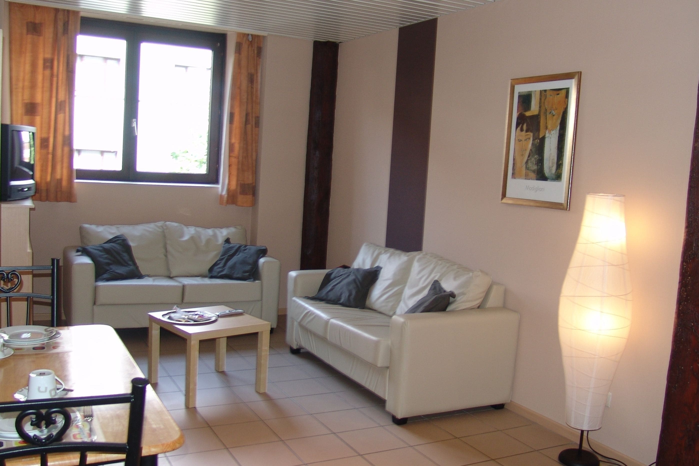 A living room with two white sofas, a wooden coffee table, a TV, and a floor lamp.