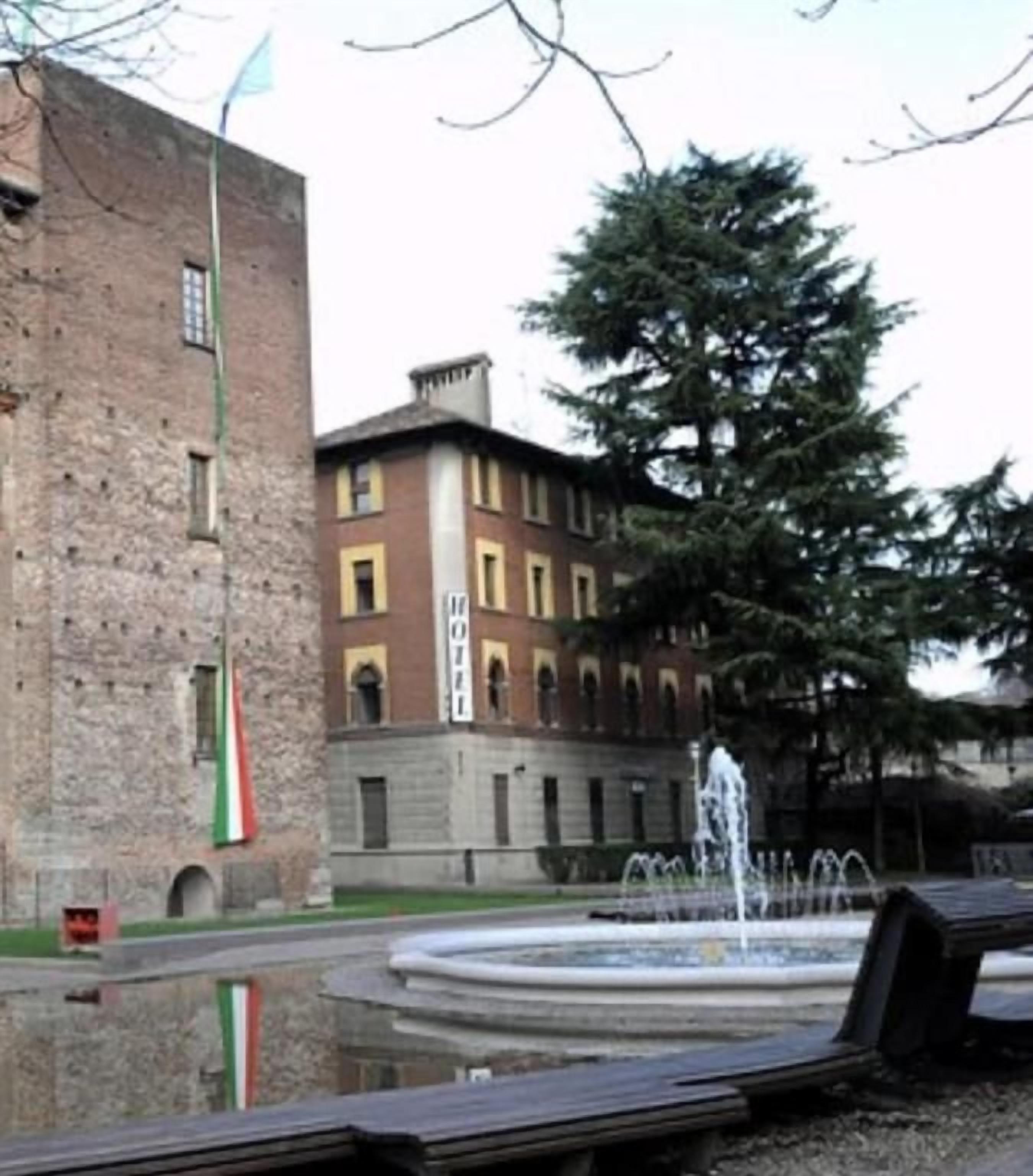 Un edificio con una fuente delantera, una bandera y un árbol.