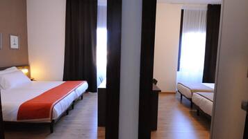 Een hotelkamer met twee bedden, een houten vloer en uitzicht op de straat.