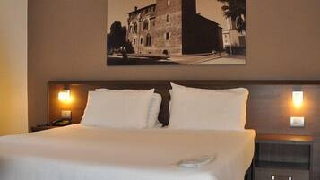 Una cama bien tendida en una habitación de hotel con un cuadro grande enmarcado sobre ella.