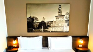 A hotel room with a large bed, two bedside tables with lamps, and a framed picture of a historic building on the wall. - Nuovo Albergo Italia (Abbiategrasso)