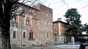 A historic building with a fountain in front, a flag, and benches. - Nuovo Hotel Italia (Abbiategrasso)