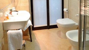 A modern bathroom with a large mirror, a sink, a toilet, and a shower area. - Nuovo Hotel Italia (Abbiategrasso)