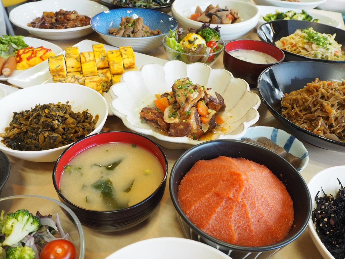 Variedad de platos en una mesa, incluyendo un tazón de sopa, un plato de tofu y otros varios con diferentes ingredientes.