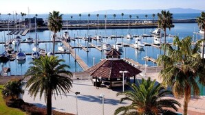 A marina with numerous boats docked, a gazebo, and palm trees.