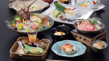 A variety of Japanese dishes including sushi, sashimi, and tempura, arranged on a table with chopsticks and a teapot.