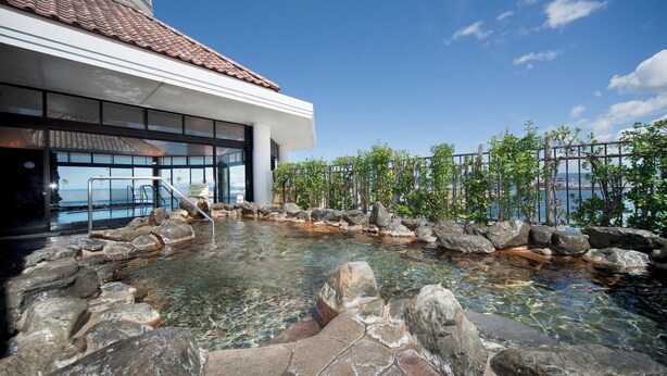 A modern building with a clear pool area surrounded by rocks and plants.