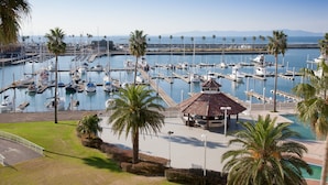 A marina with boats docked, palm trees, and a gazebo.