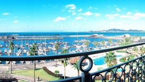 A marina with numerous boats docked, a clear blue sky, and a distant mountain range.