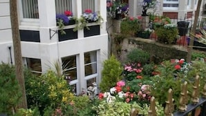 A multi-story building with balconies adorned with various flowers and plants.