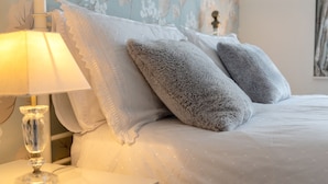 A neatly made bed with fluffy pillows and a bedside lamp on a white nightstand.