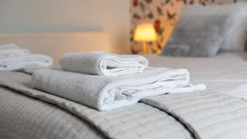 Una cama bien hecha con toallas blancas dobladas y una colcha acolchada.