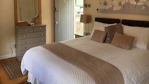 Une chambre à coucher comprenant un lit, une commode, un ventilateur de plafond et une porte donnant sur l’extérieur.