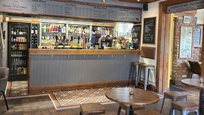 Un espace bar avec des tabourets et un comptoir où sont exposées différentes boissons.